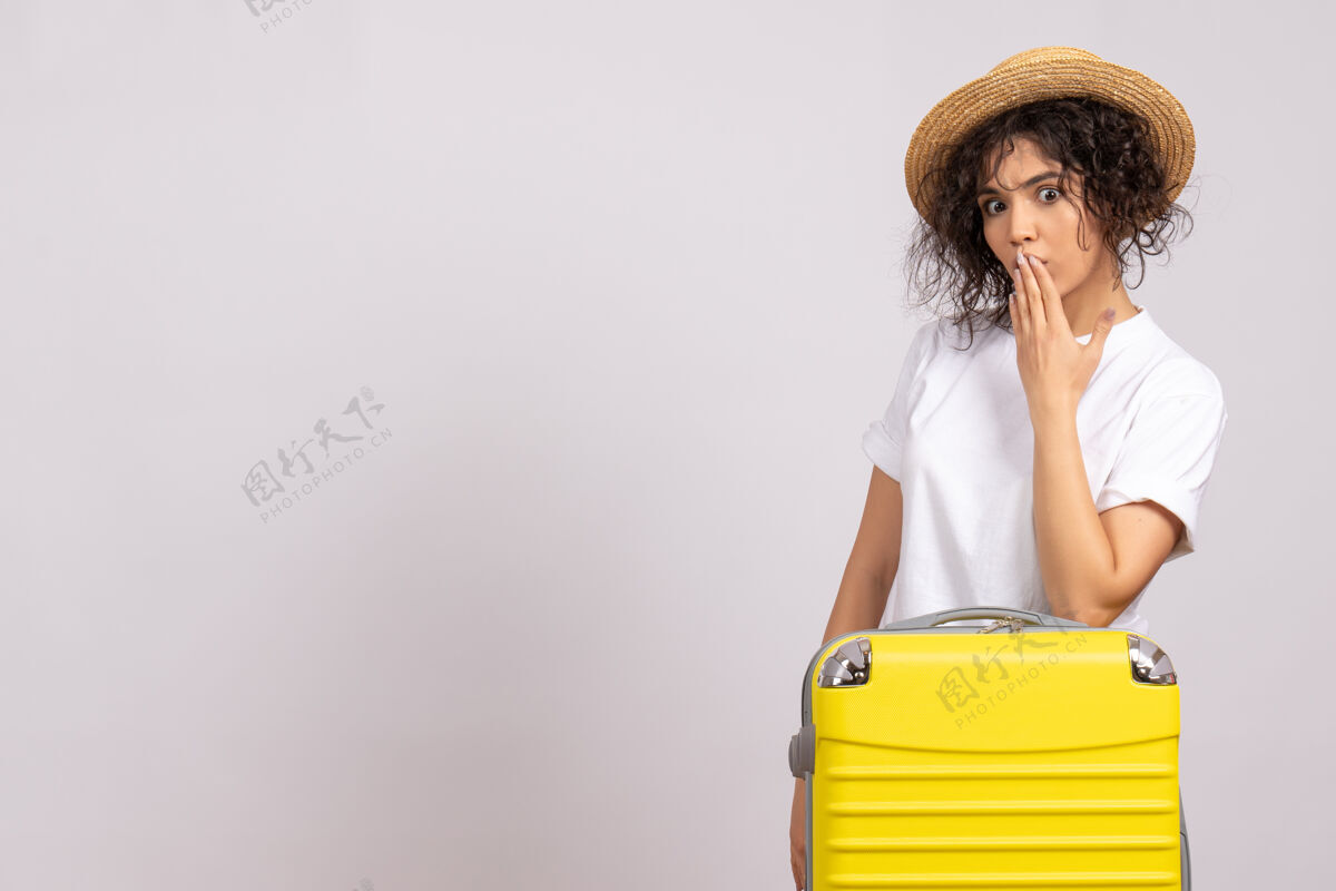 飞行正面图年轻女性带着黄色的包准备旅行 惊讶地坐在白色背景的度假旅行彩色休息航班旅游飞机上人美丽旅行
