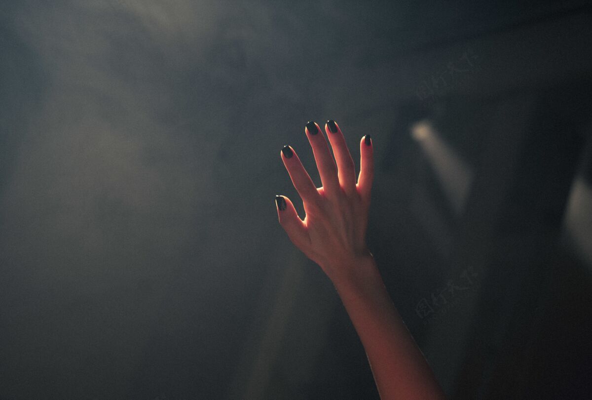 手特写一个女人的手覆盖着黑暗模糊的背景灯身体手指女性