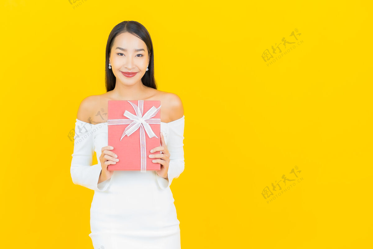 盒子黄墙上挂着红色礼盒的亚洲商界年轻美女画像脸年轻有趣