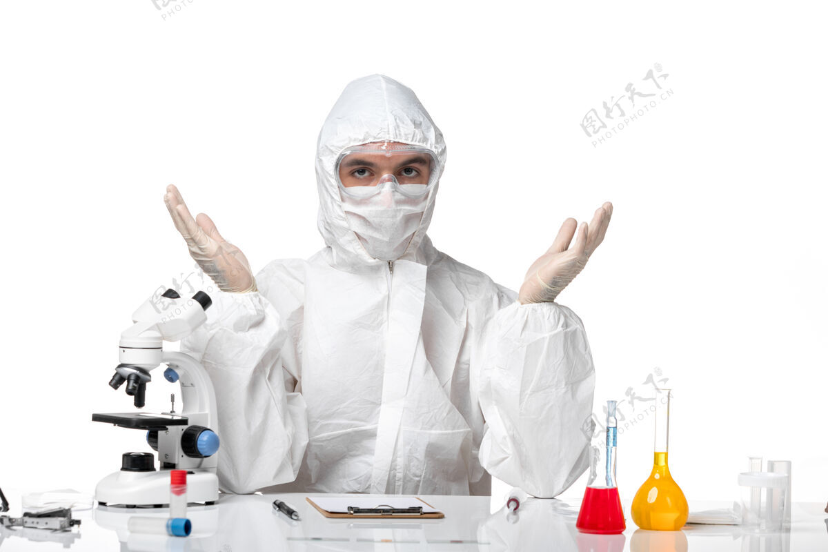 到期正面图：男医生穿着防护服 戴着口罩 因为科维德正坐在白色的桌子上制服医生正义