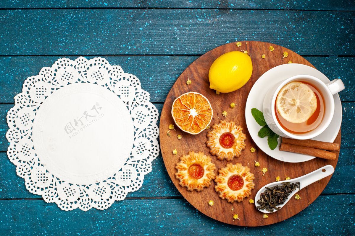 杯子蓝色桌子上的一杯茶 上面放着饼干和柠檬陶瓷器皿餐厅碗