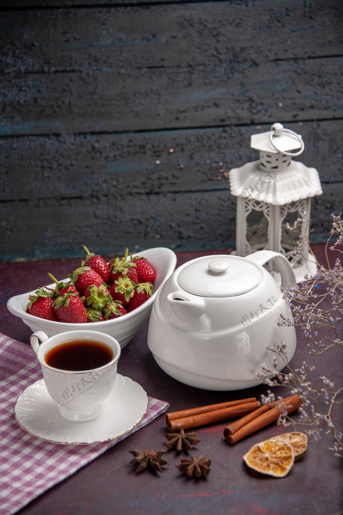 生的前视一杯茶 用肉桂和草莓放在深色的茶面上喝水果色的茶炊具茶器皿