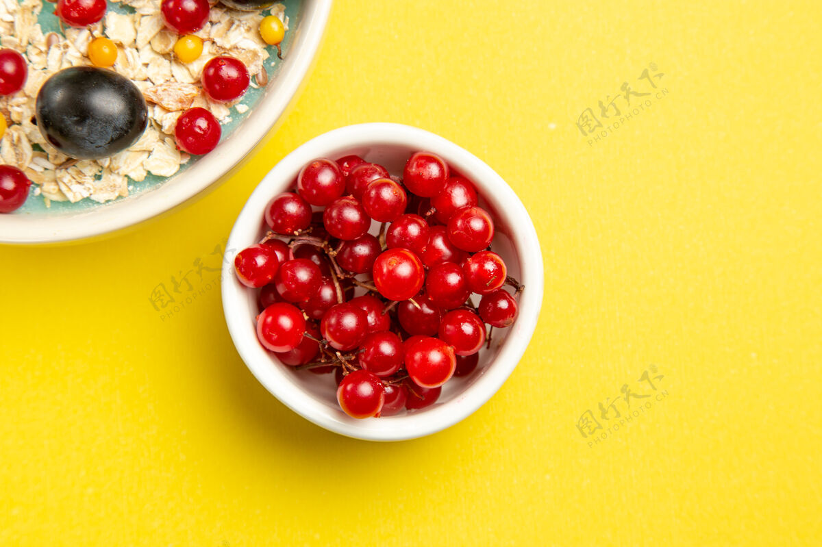 葡萄干顶部特写镜头：黄色桌子上一碗碗开胃的红醋栗饮食浆果食品