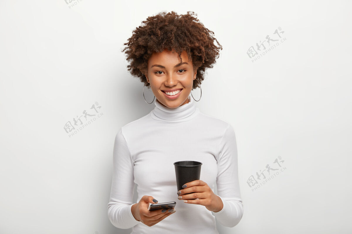 人一个留着非洲发型的漂亮女人 手里拿着现代手机和外卖咖啡 闲暇时间上网聊天饮料非洲咧嘴笑