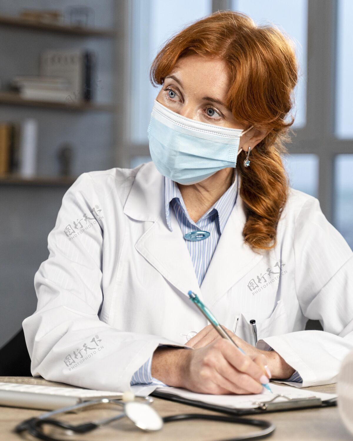 医生女医生戴着医用口罩在办公桌前写处方的正面图全科医生处方工作