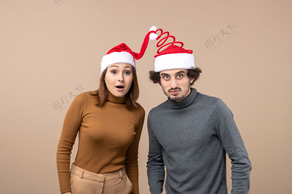 节日节日喜庆和派对理念-快乐可爱的年轻夫妇戴着团结一致的圣诞老人帽上灰色工人职业圣诞节