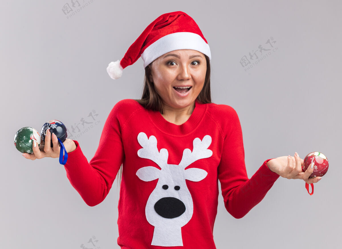 圣诞节兴奋的年轻亚洲女孩戴着圣诞帽和毛衣拿着圣诞树球隔离在白色背景树毛衣亚洲人