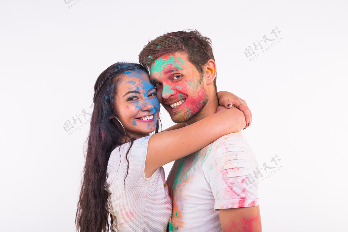 多彩笑容可掬的女人和男人摆着五颜六色的粉在他们的脸上女人欢乐艺术