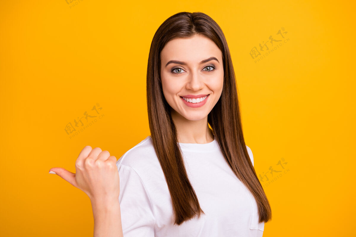 学生照片惊人的好生意女士指导拇指手指侧空空间酷销售提供购物穿着休闲白色t恤隔离明亮的黄色墙壁休闲微笑建议