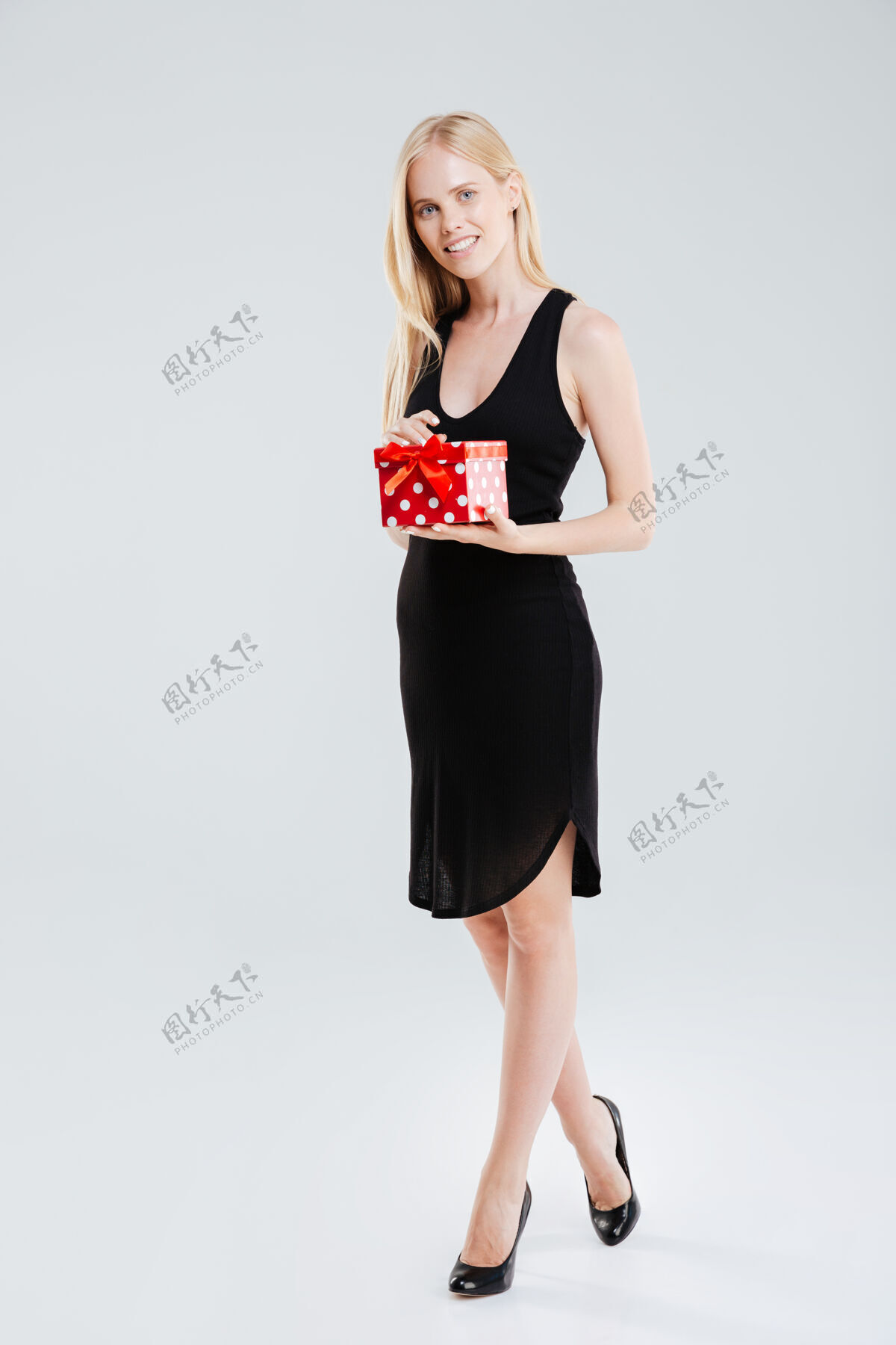 时尚一个微笑的年轻女子拿着礼品盒在白色背景上孤立的全长肖像休闲衣服女性