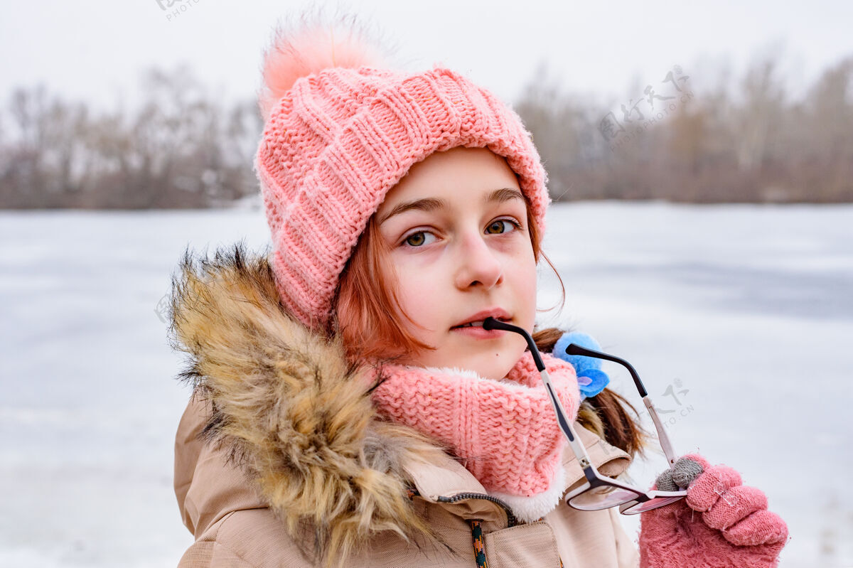 雪站在冬天的少女女孩手里拿着她的眼镜一个好孩子的画像美丽模特自然