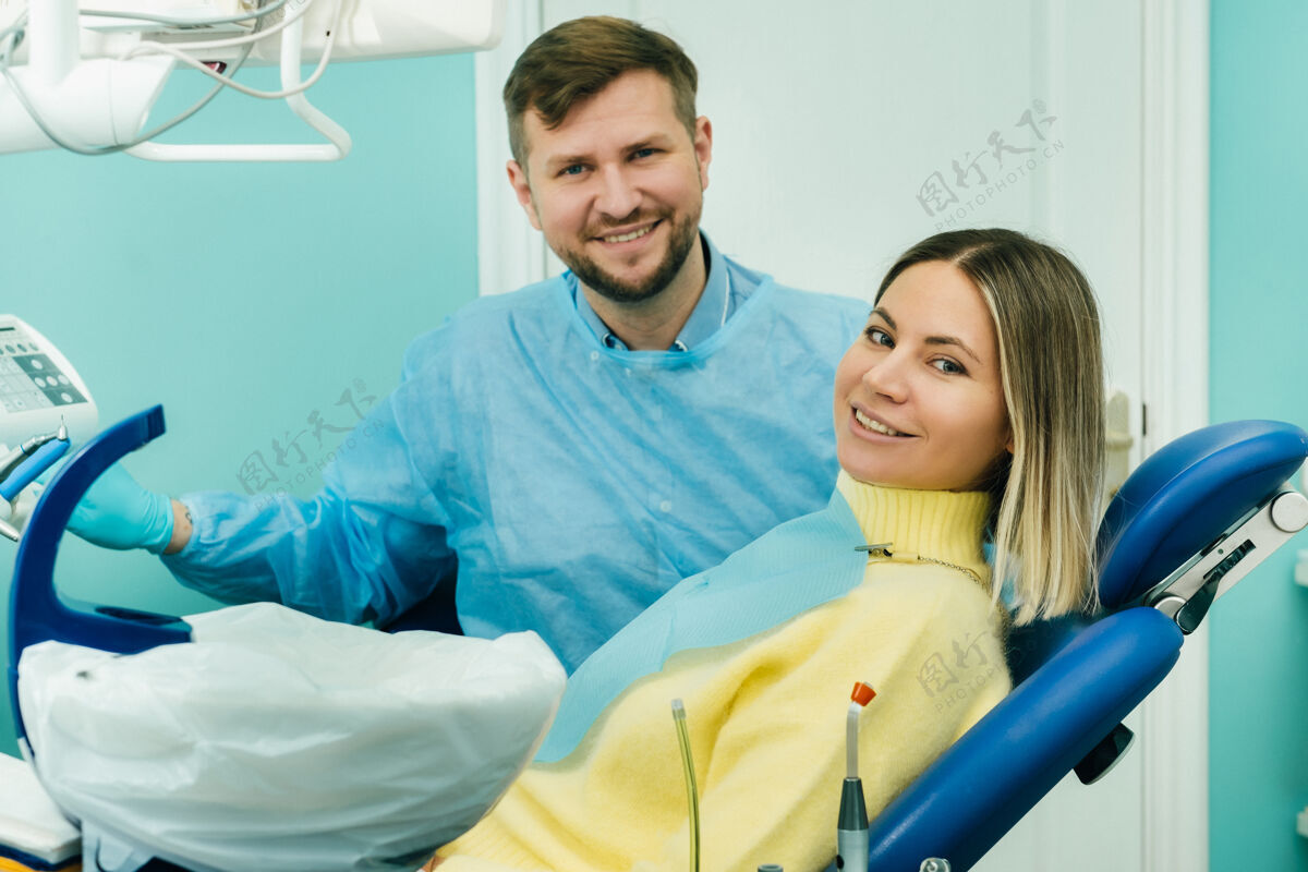 快乐美丽的女病人坐在牙医的椅子上 用她的手向全班展示患者年轻口腔
