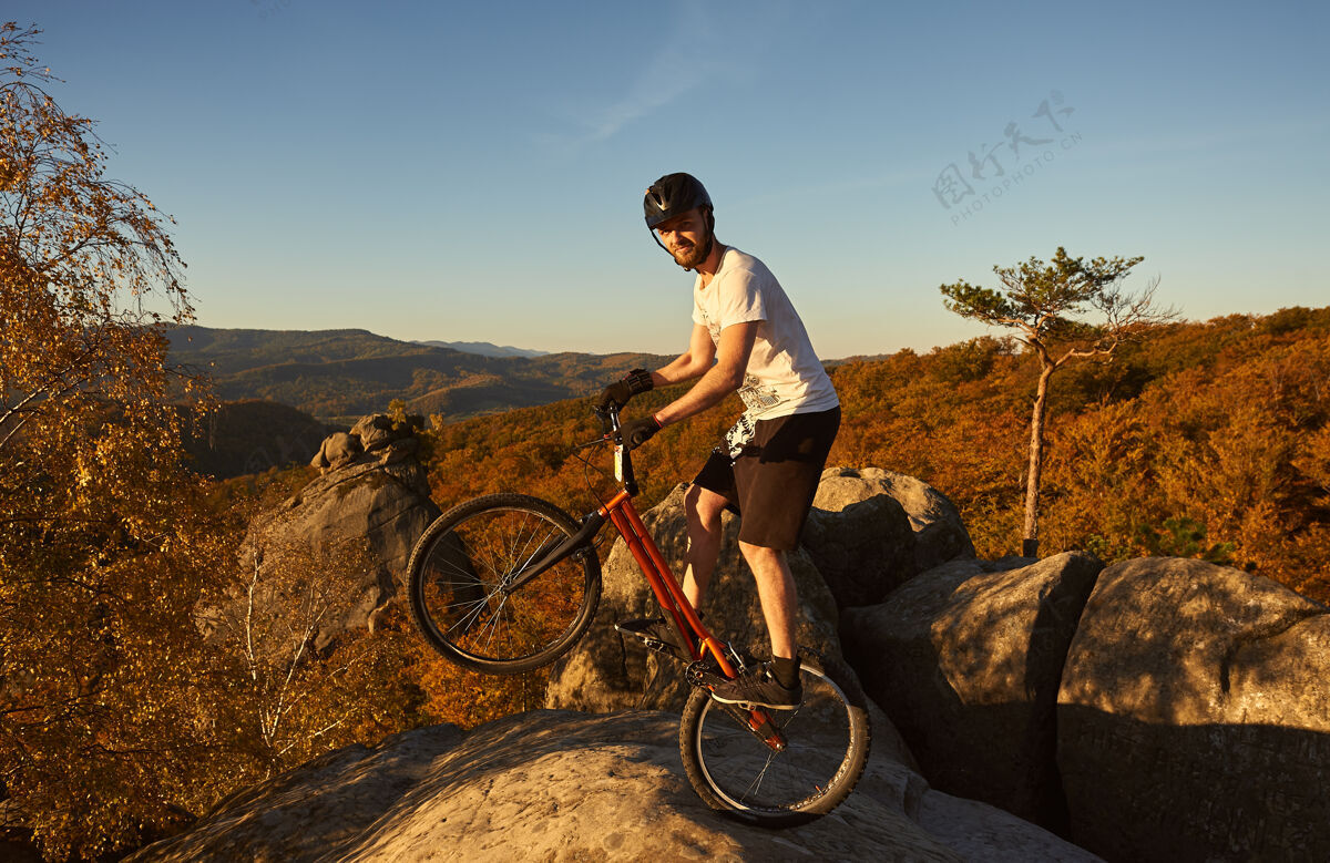 骑手在日落时分 职业自行车手在试骑自行车上保持平衡站立危险活动