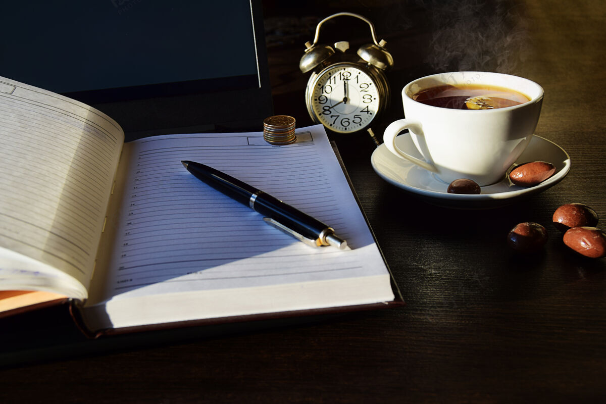 笔记本电脑远程在线工作 带日记和一杯茶的商务概念笔记本电脑聊天在线工作