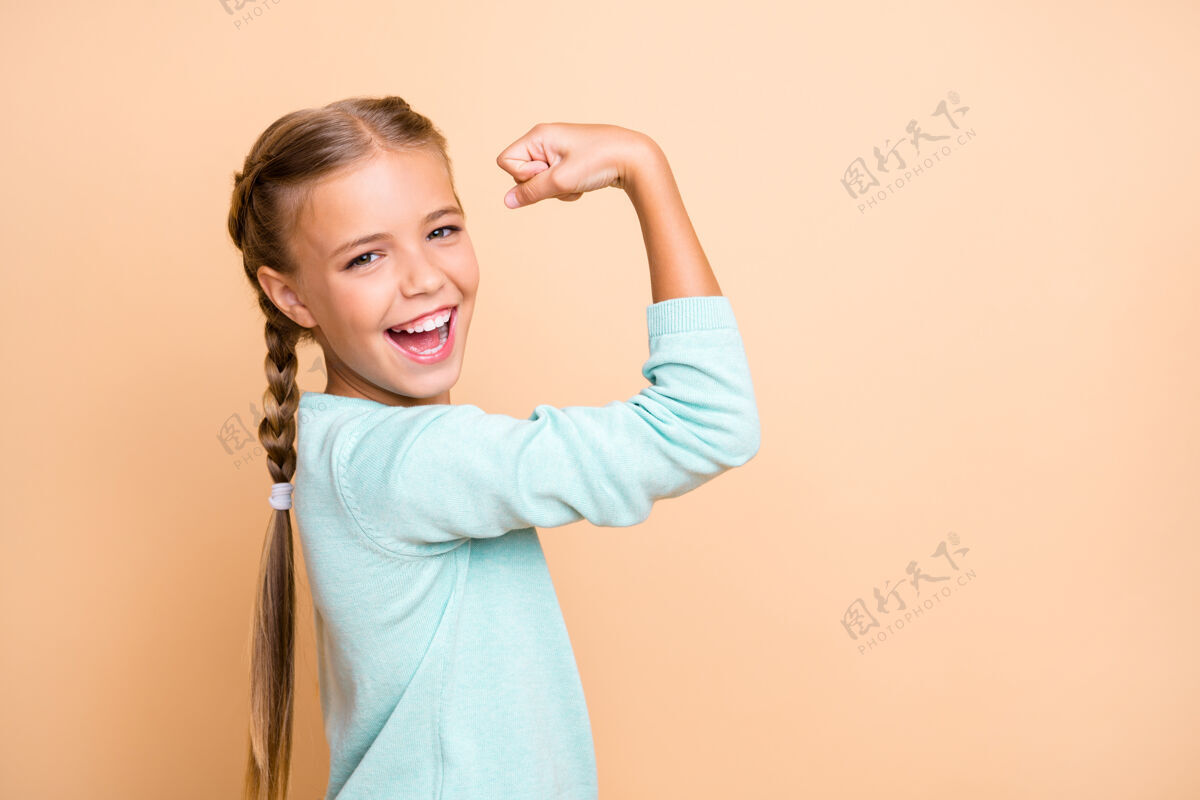 水鸭美丽兴奋的小女士雄心勃勃的人举起拳头庆祝成功的训练锻炼穿蓝色套头衫隔离米色粉彩墙的资料照片时尚女性人类
