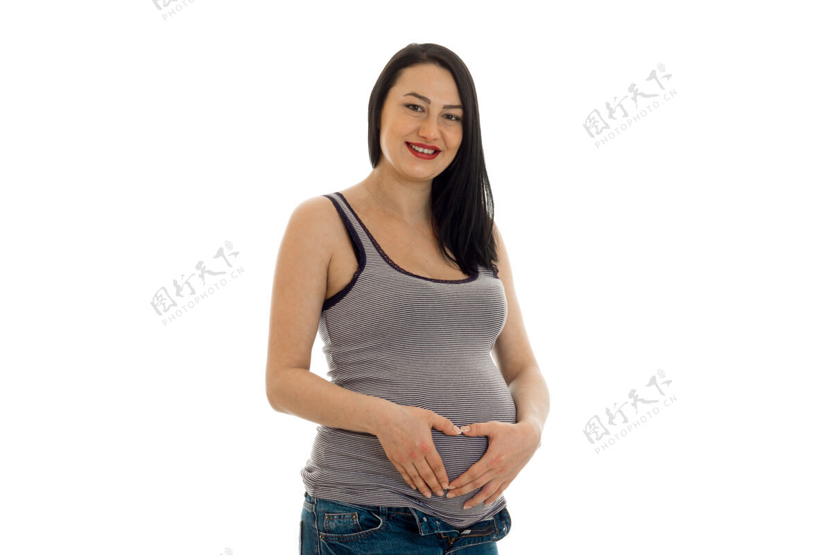 未出生年轻快乐的怀孕的黑发女人在白色的墙上摆着孤立的姿势家庭人漂亮