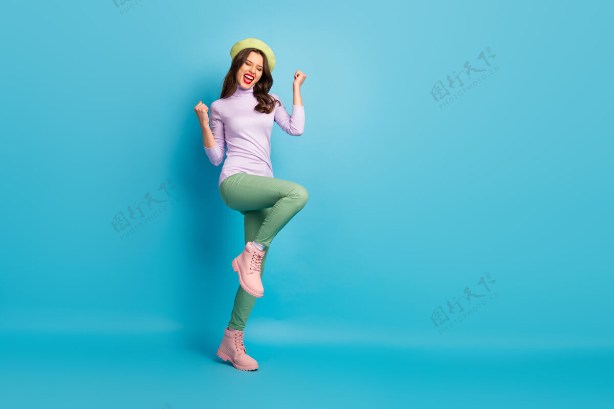 胜利美丽的旅游小姐走在街上庆祝访问梦想之城国家穿绿色贝雷帽紫色套头衫长裤鞋孤立的蓝色墙壁时尚贝雷帽休闲