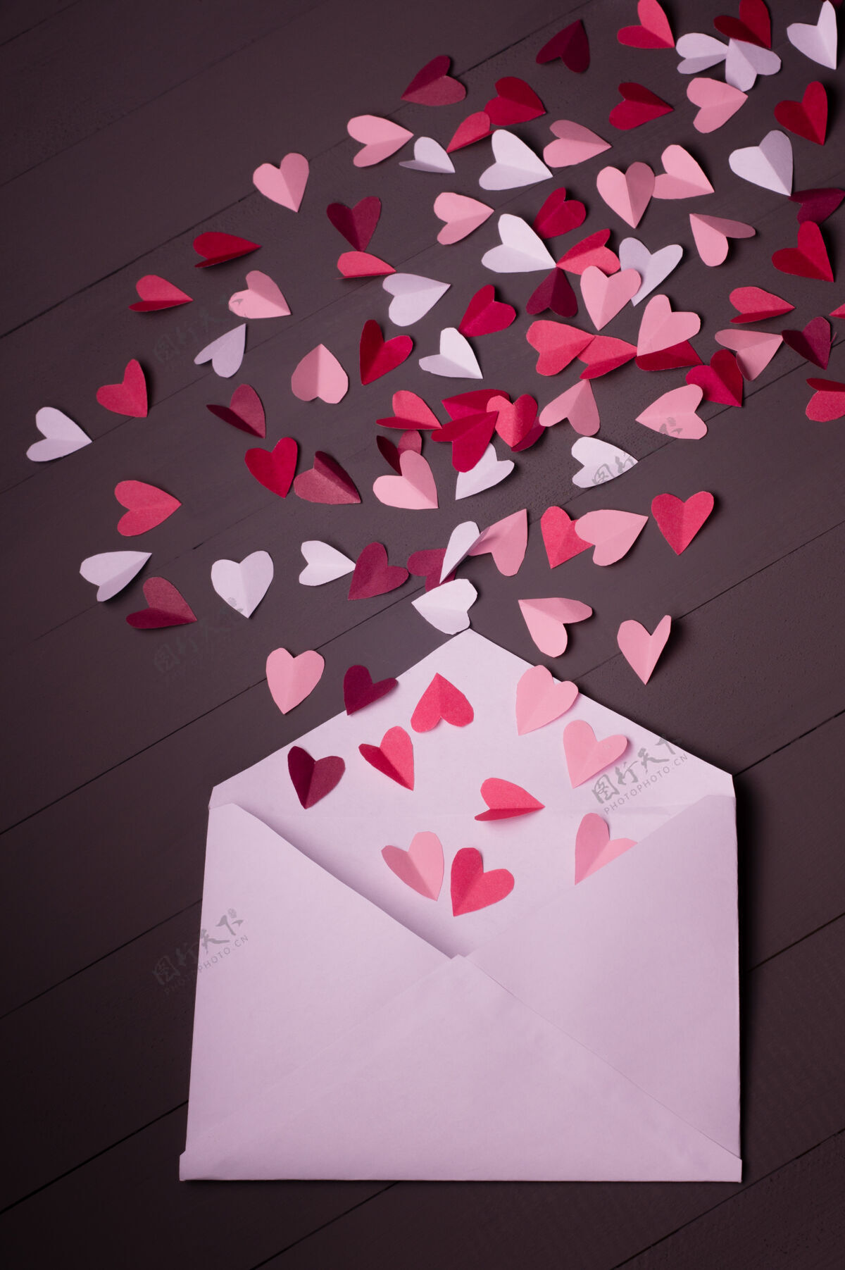 信封红色 白色和粉色的纸心装在灰色木质的白色信封里信纸平铺