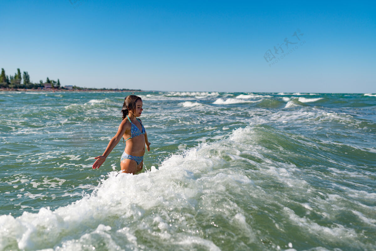 飞溅在一个阳光明媚温暖的夏日 活泼快乐的小女孩在喧闹的海浪中嬉戏梦想想象风