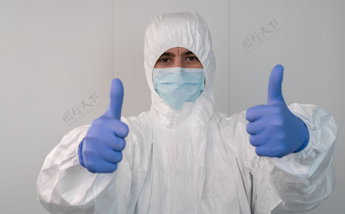 阳性特写镜头：一个穿着防护服的护士用手做着竖起大拇指的手势冠状病毒大流行 冠状病毒19医院里的医护人员带着ppe手套疾病护士