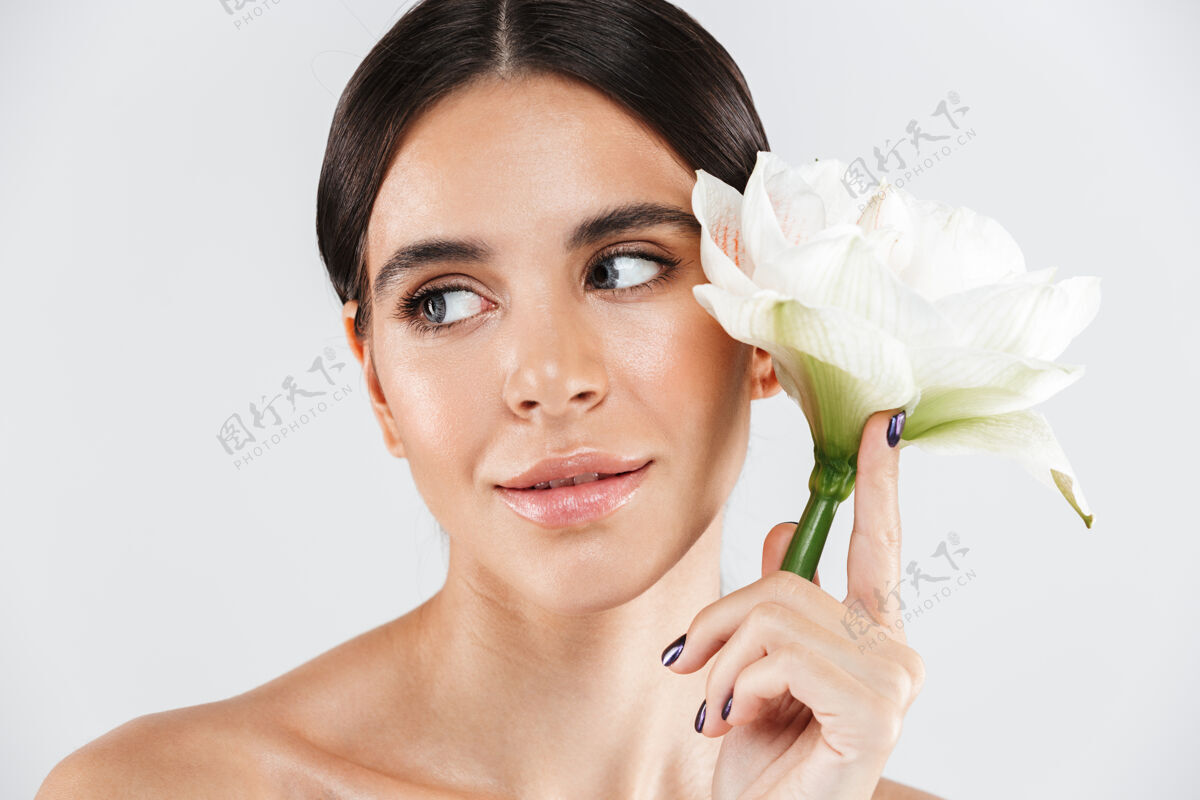 化妆品美丽的肖像一个迷人的感官健康的女人站在隔离的白色墙壁 摆出一朵花身体年轻白种人