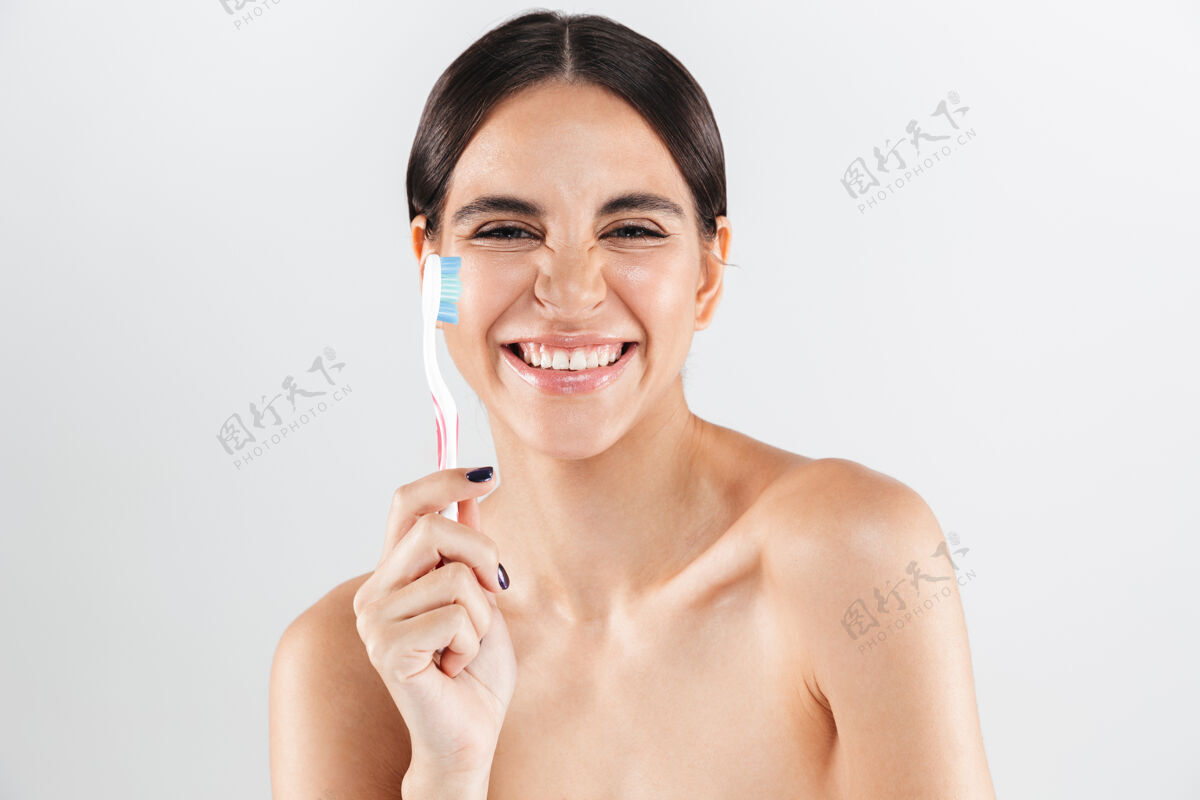 成人美丽的肖像画 一个美丽健康的女人孤立地站在白色的墙上 展示一把牙刷快乐吸引力女人