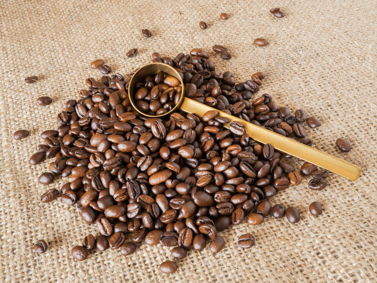 质地咖啡豆与黄金测量勺和量杯亚麻质地的背景咖啡因亚麻质地马克杯