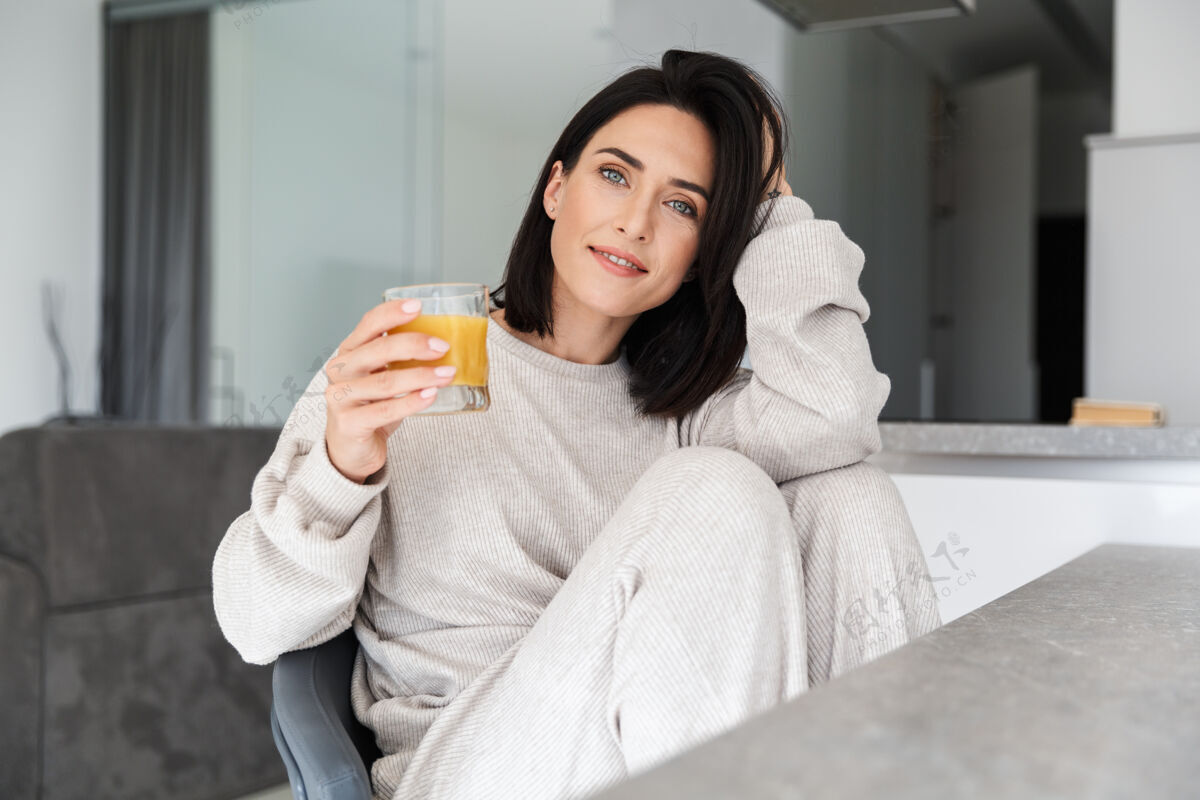 深褐色一位30多岁的白人妇女一边喝着橙汁 一边在明亮的现代房子里休息成人消遣舒适