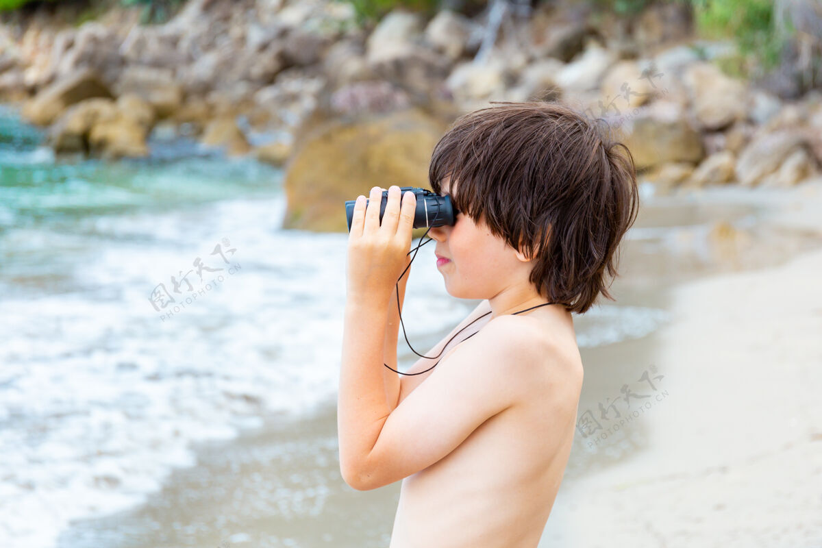 休闲一个小男孩呆在海边的海滩上 用望远镜看东西发现玩海洋