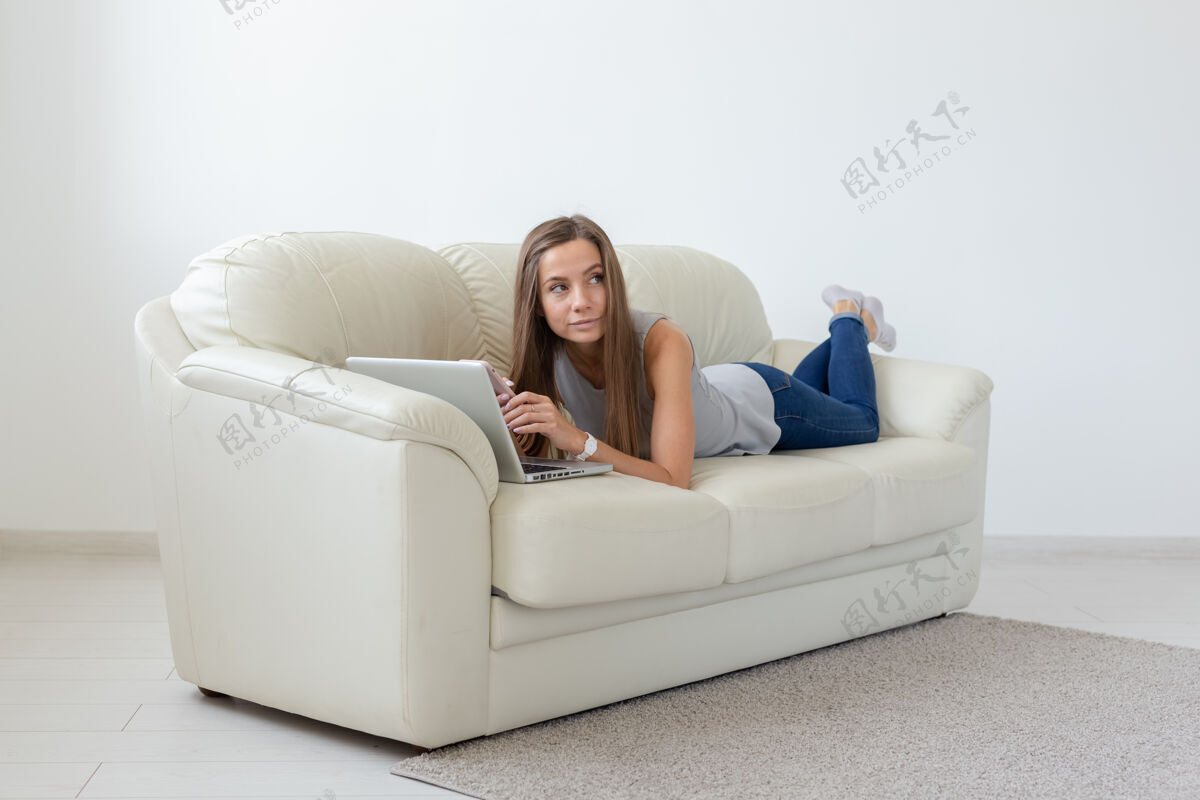 女性技术 放松和自由职业者概念漂亮躺在沙发上用笔记本电脑工作的年轻女子科技打字休闲