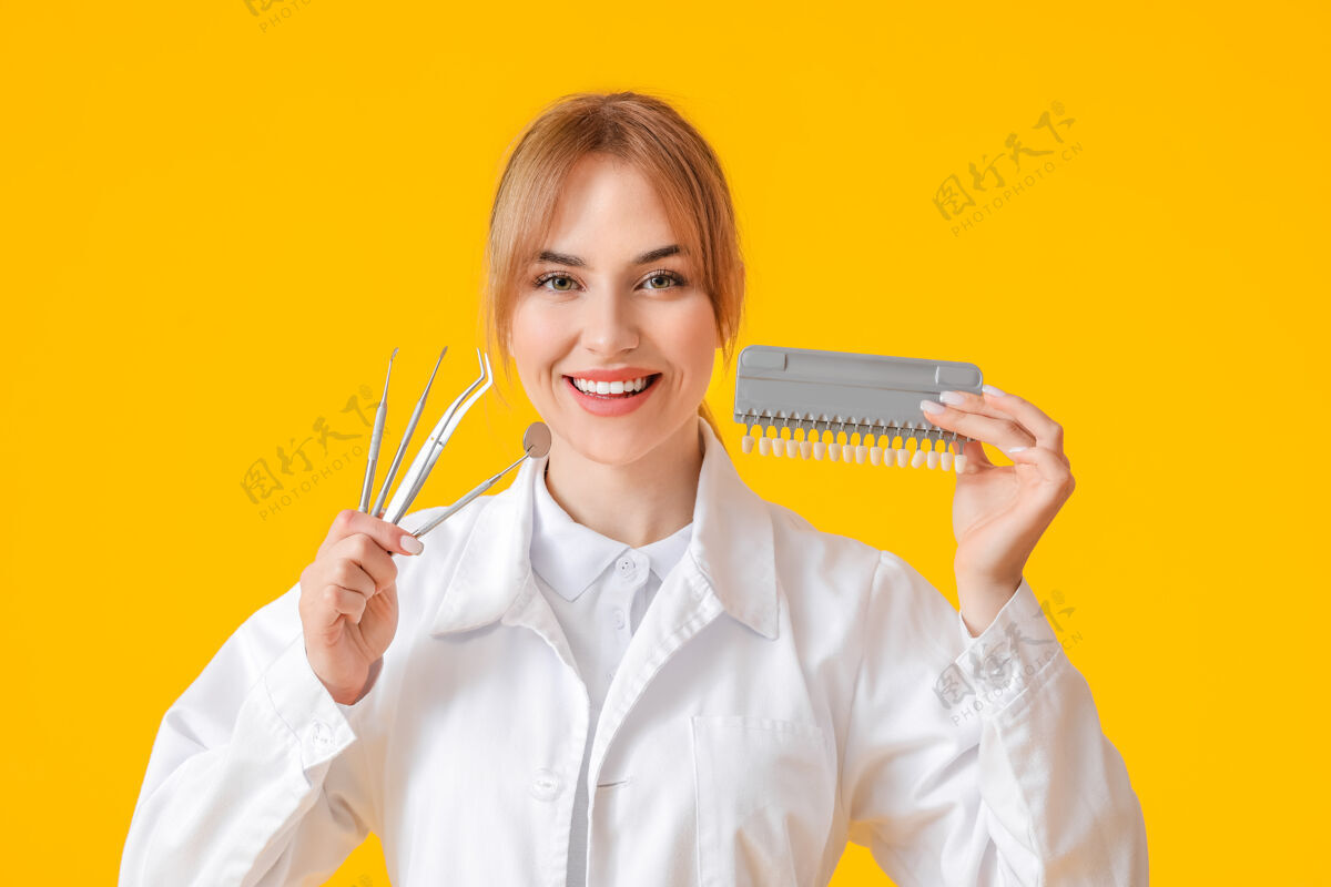 肖像女牙医用工具和牙齿颜色表在黄色表面正畸图表人