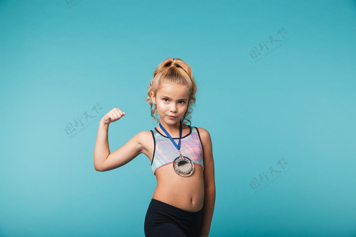参与快乐的小运动女孩 戴着金牌 庆祝战胜蓝墙荣誉成功地点
