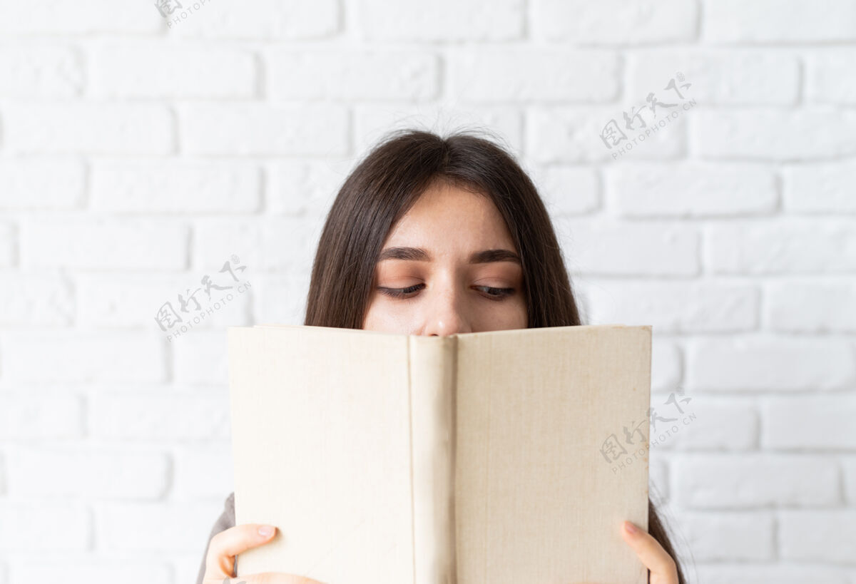 美丽一个女人拿着一本打开的书在她面前的特写镜头青年衬衫休闲