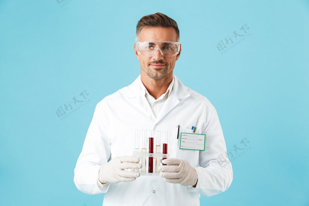 职业自信的男医生穿着制服 戴着眼镜 站在蓝色的墙上 拿着烧杯玻璃肖像化学