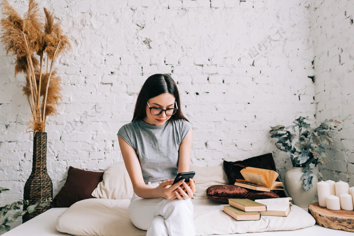 女性戴眼镜的白人年轻女子在家里沙发上休息时使用手机互联网室内休闲
