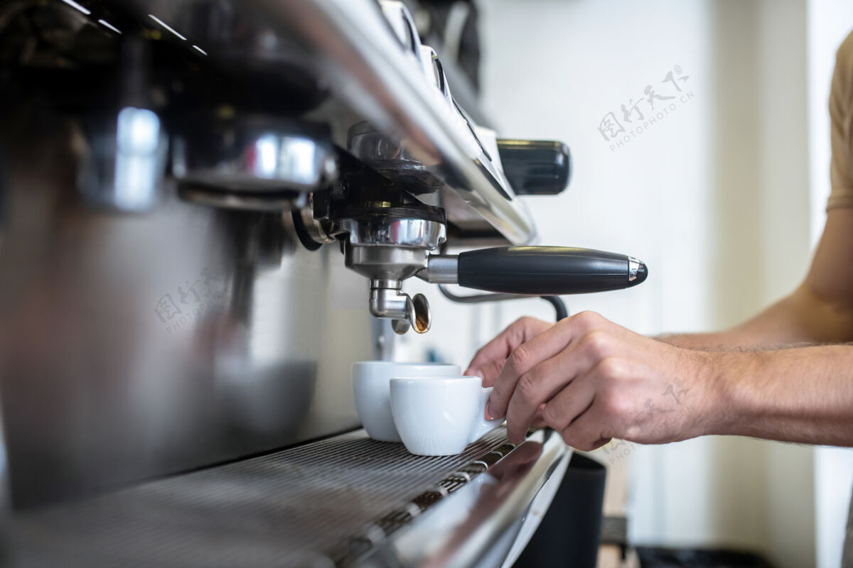 自营职业制作咖啡男双手将两个白色杯子放进室内咖啡机 看不到脸整洁按钮做