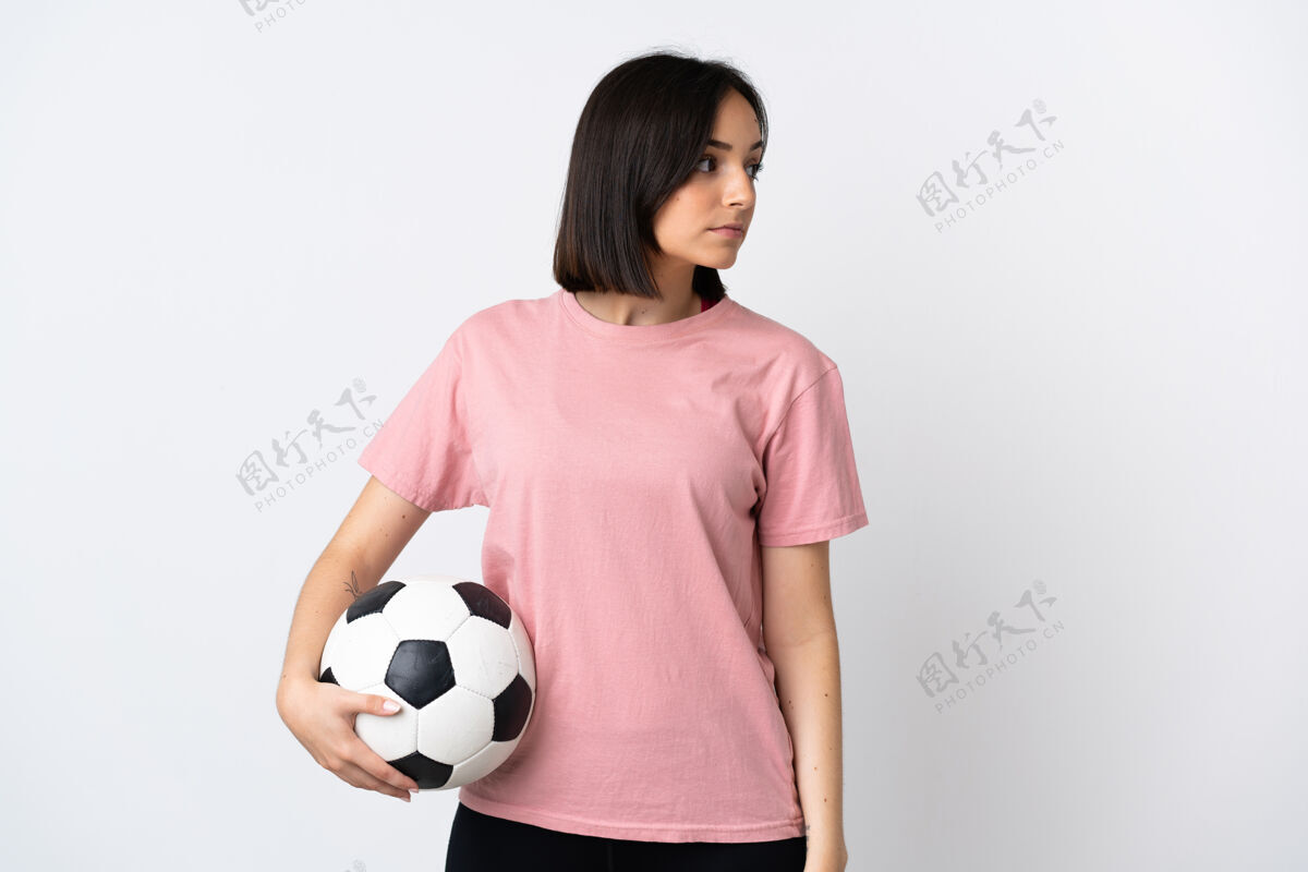 女孩年轻的白种女人拿着足球被隔离在白墙上运动员女黑发