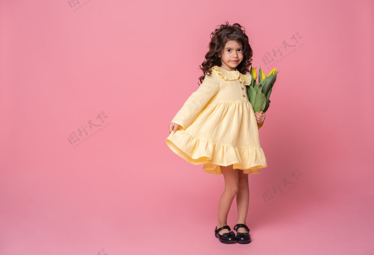 花粉红工作室里一个穿着黄色裙子的微笑女孩庆祝情感美丽