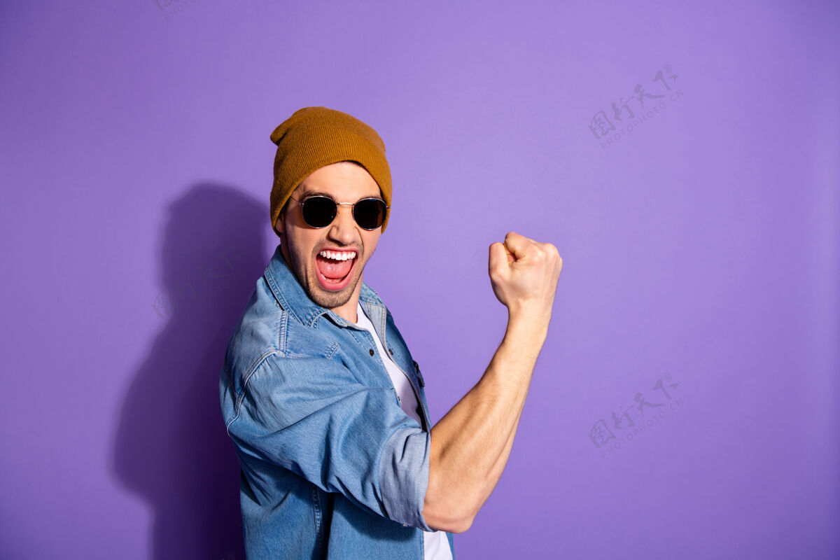 积极照片中的快乐迷人英俊的疯子向你展示了他的肌肉肱二头肌尖叫与胜利戴帽头饰隔离紫色生动的色彩背景阳刚肌肉男人
