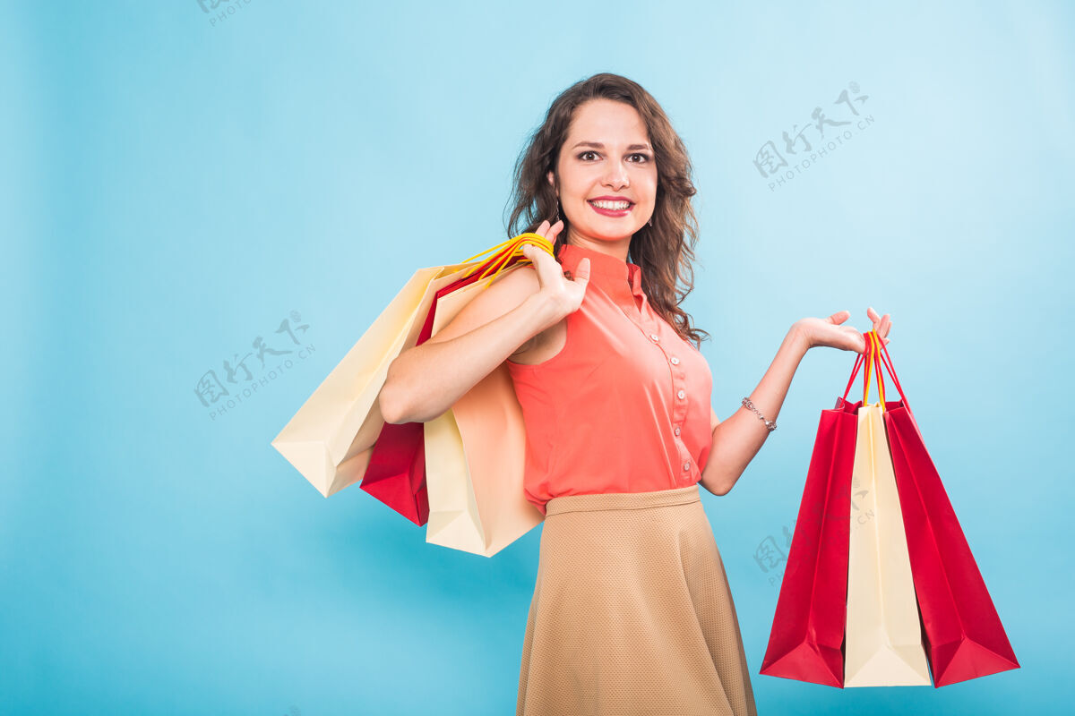 商场购物的女人拿着包 孤零零地站在蓝色的墙上购物高加索女性