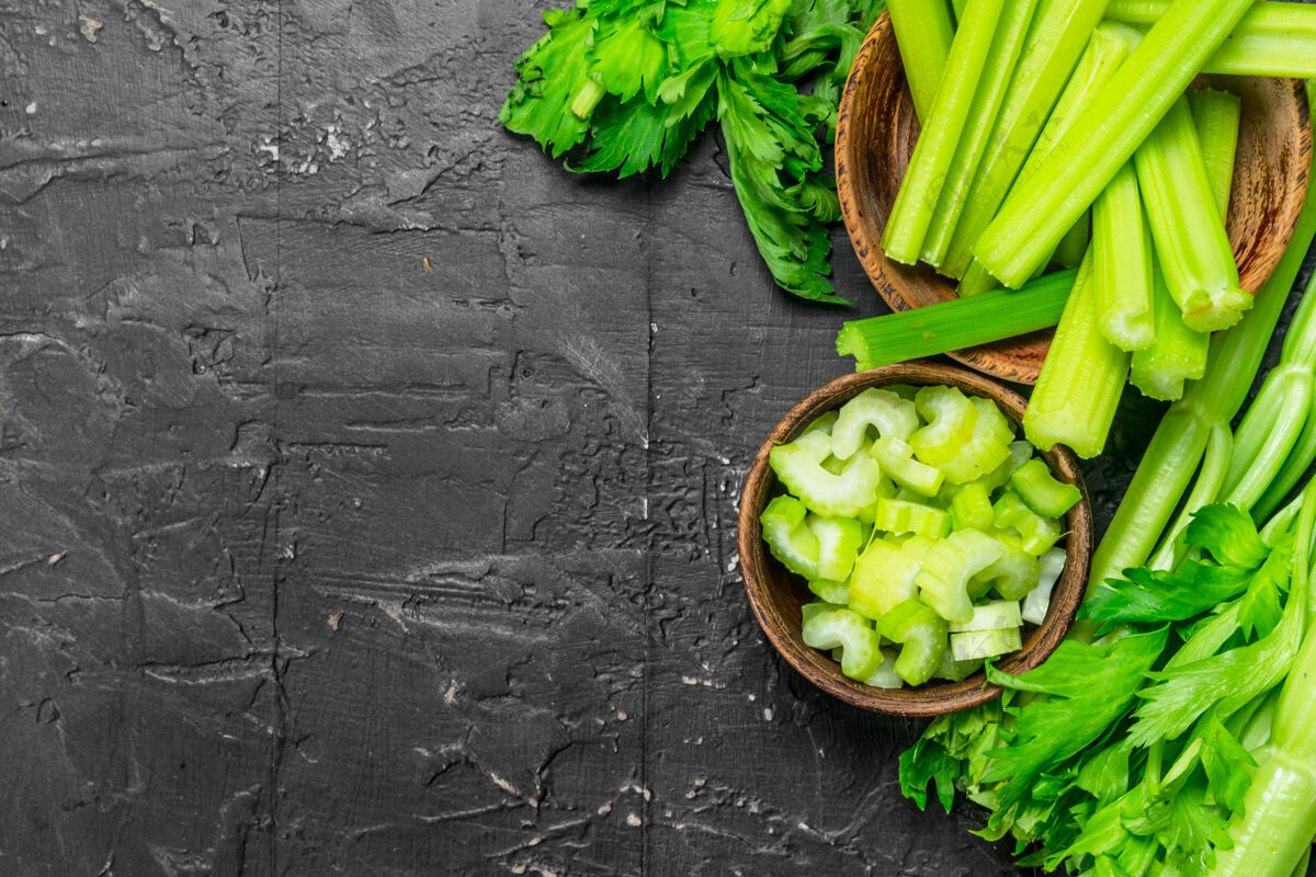 吃把芹菜放在木桌上的木碗里营养棒素食者