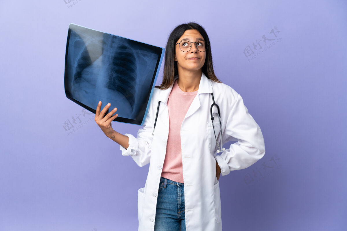 成人年轻的女医生拿着X光片抬头看护理人专业