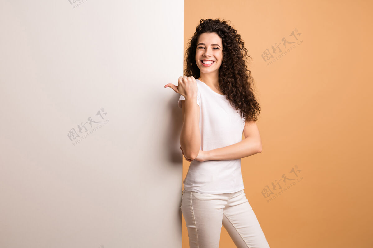 发型照片中的神奇女士在空的折扣横幅上指指点点站在大白板附近穿着白色休闲服隔离米色粉彩背景女孩新闻秀