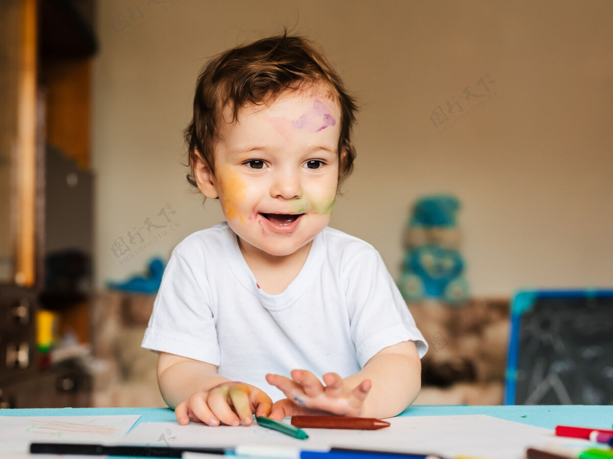 学校一个小男孩用彩色记号笔在一张纸上画画学习年轻素描