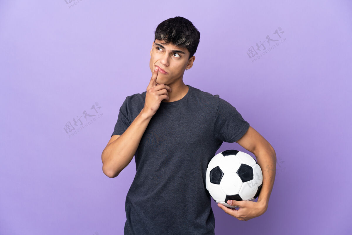 怀疑一个年轻的足球运动员 在孤立的紫色背景下 一边抬头一边怀疑表达游戏玩