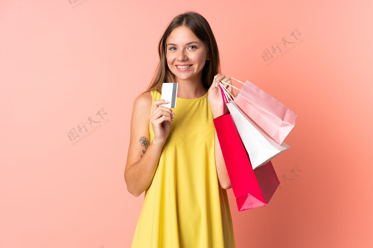 销售一位年轻的立陶宛妇女 手拿购物袋和信用卡 被隔离在粉色背景下银行电子商务粉色