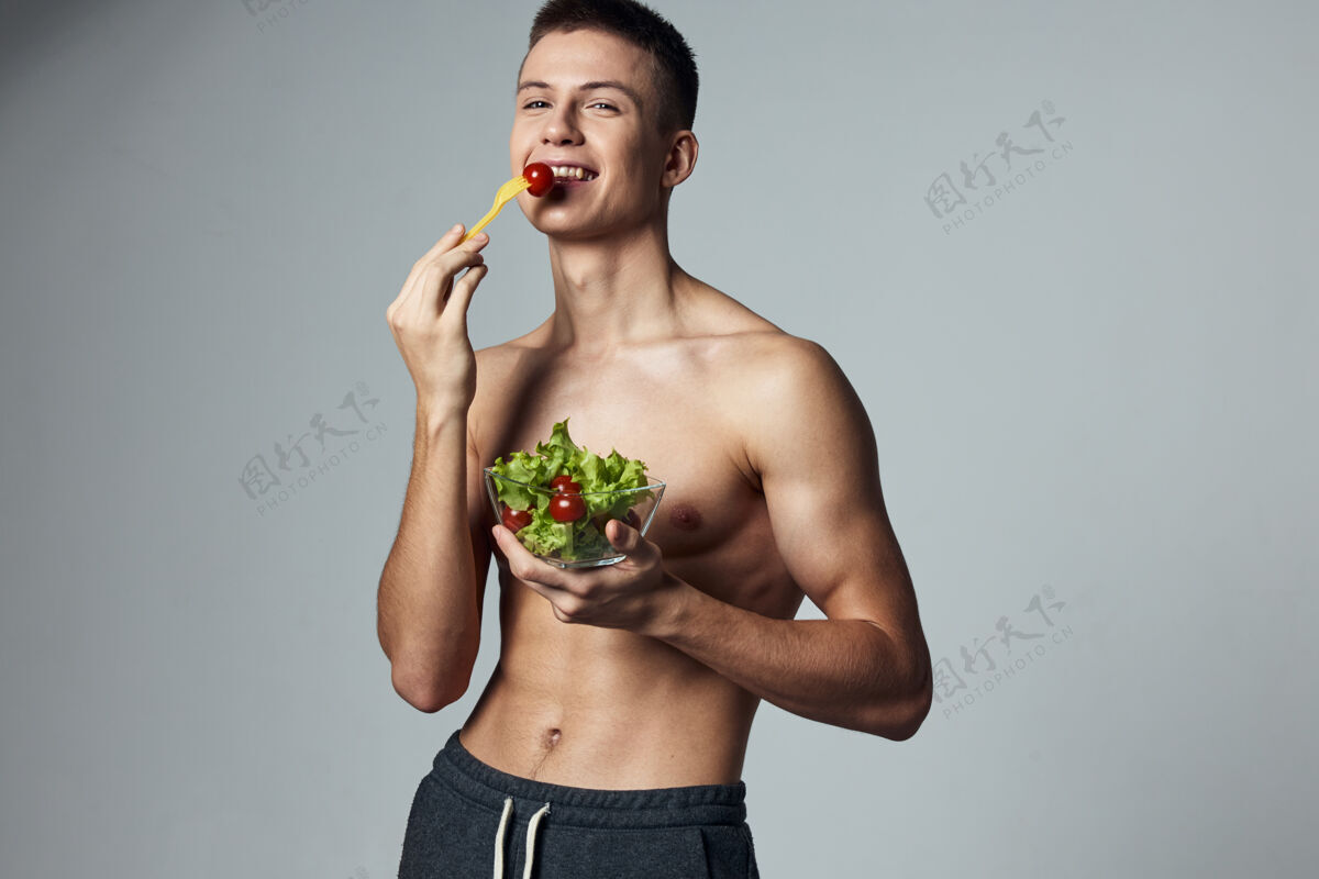 年轻有趣的运动家伙沙拉健康食品不规则的锻炼视图盘沙拉素食者二头肌