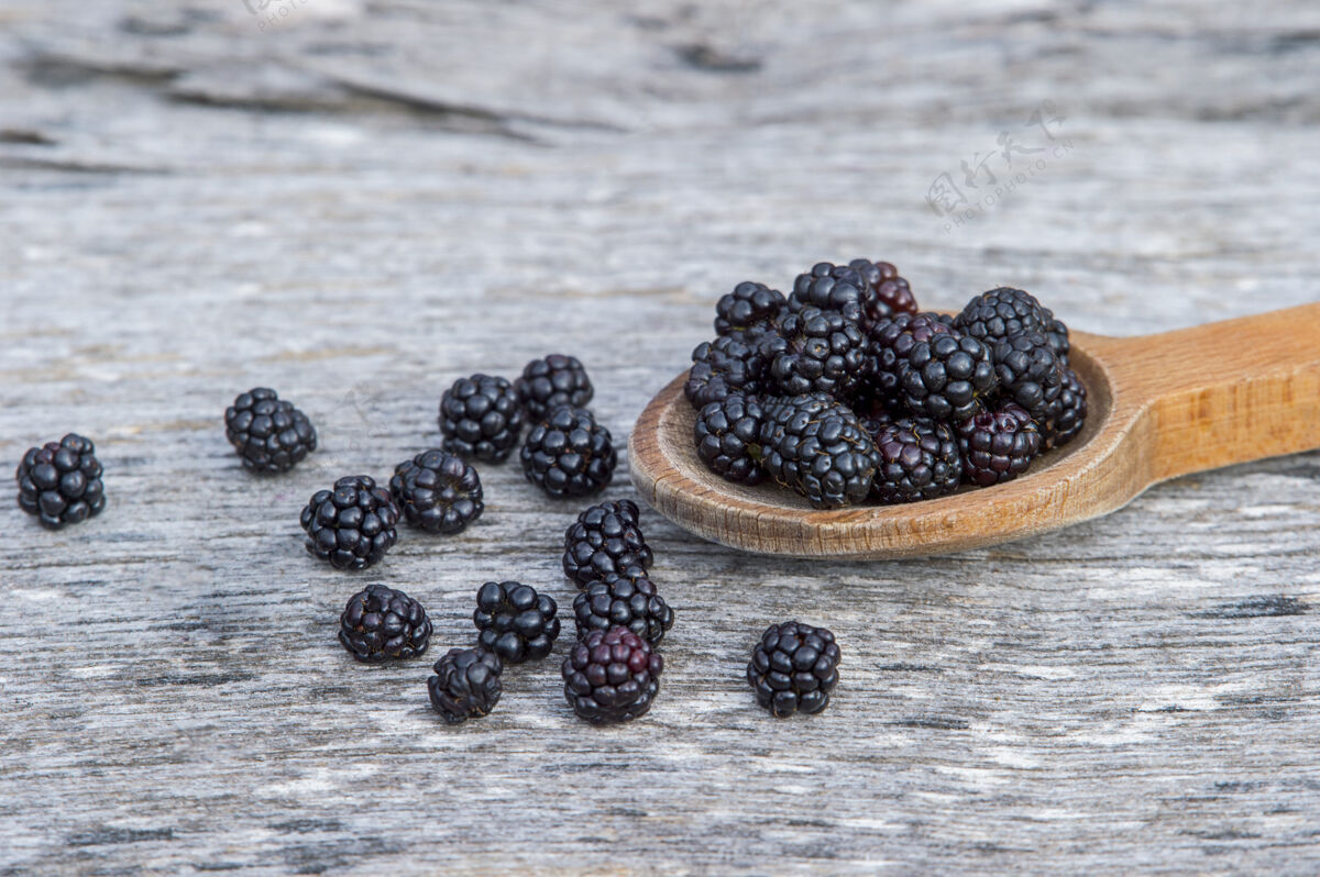物体在古老的木制背景上 用木勺盛着成熟的黑莓多汁的大的成熟的黑莓