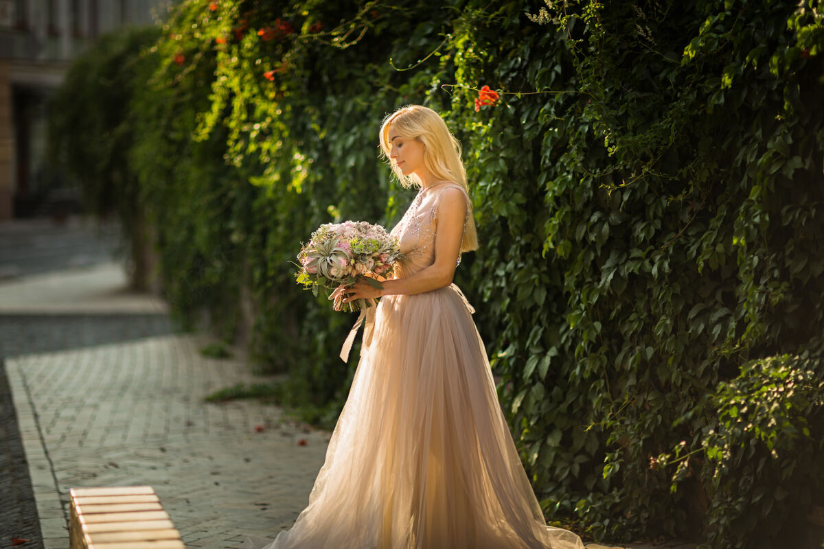 花束一个穿着灰色婚纱的优雅漂亮女人的肖像 在花园里摆姿势街头新娘捧着一束柔和的鲜花和绿叶女性年轻鲜花