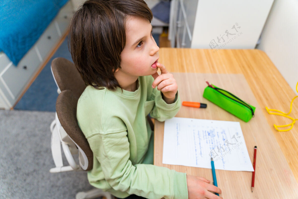 锻炼小男孩坐在桌子旁做作业家集中思考任务的孩子兴趣.家庭教育教育房子学生写作